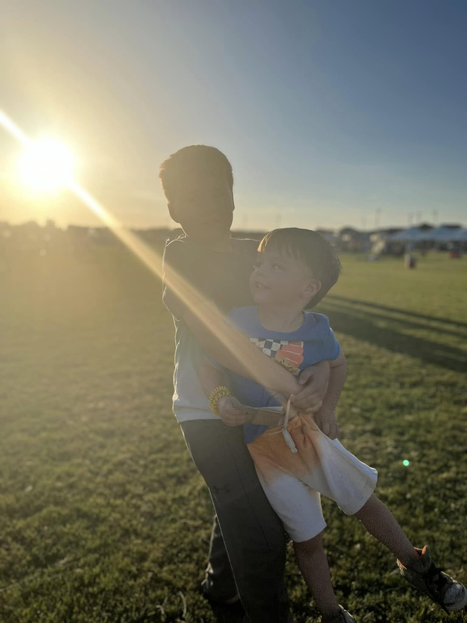 Parent holding a child in a sunlit field