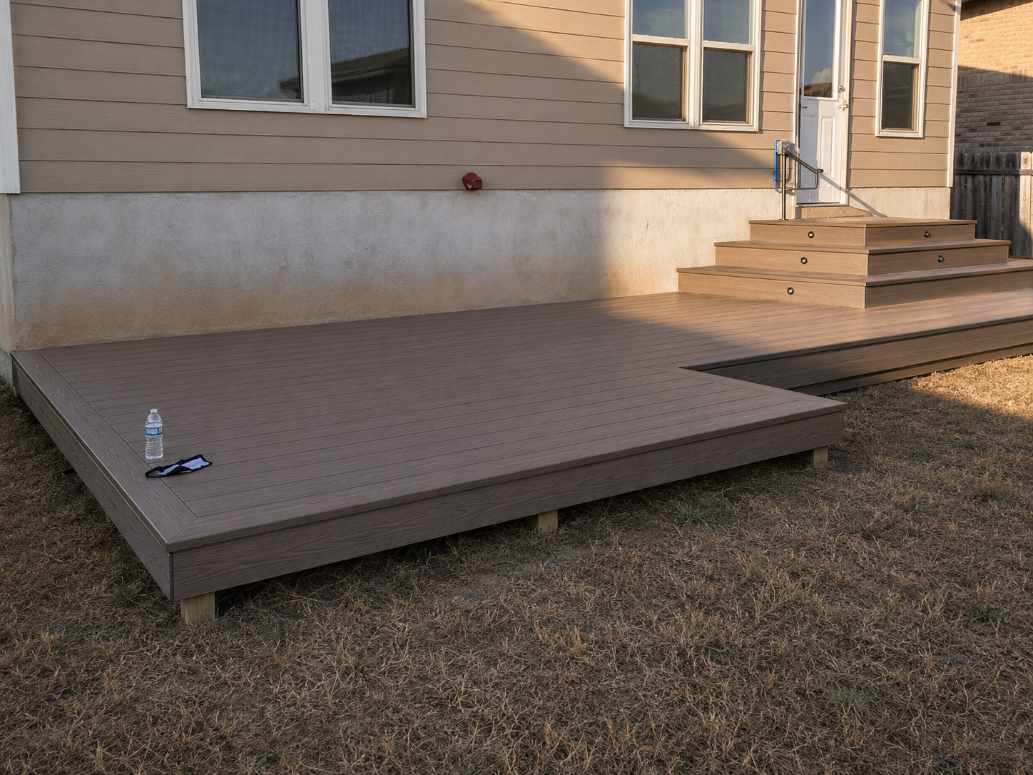 Completed deck with built-in steps beside a home