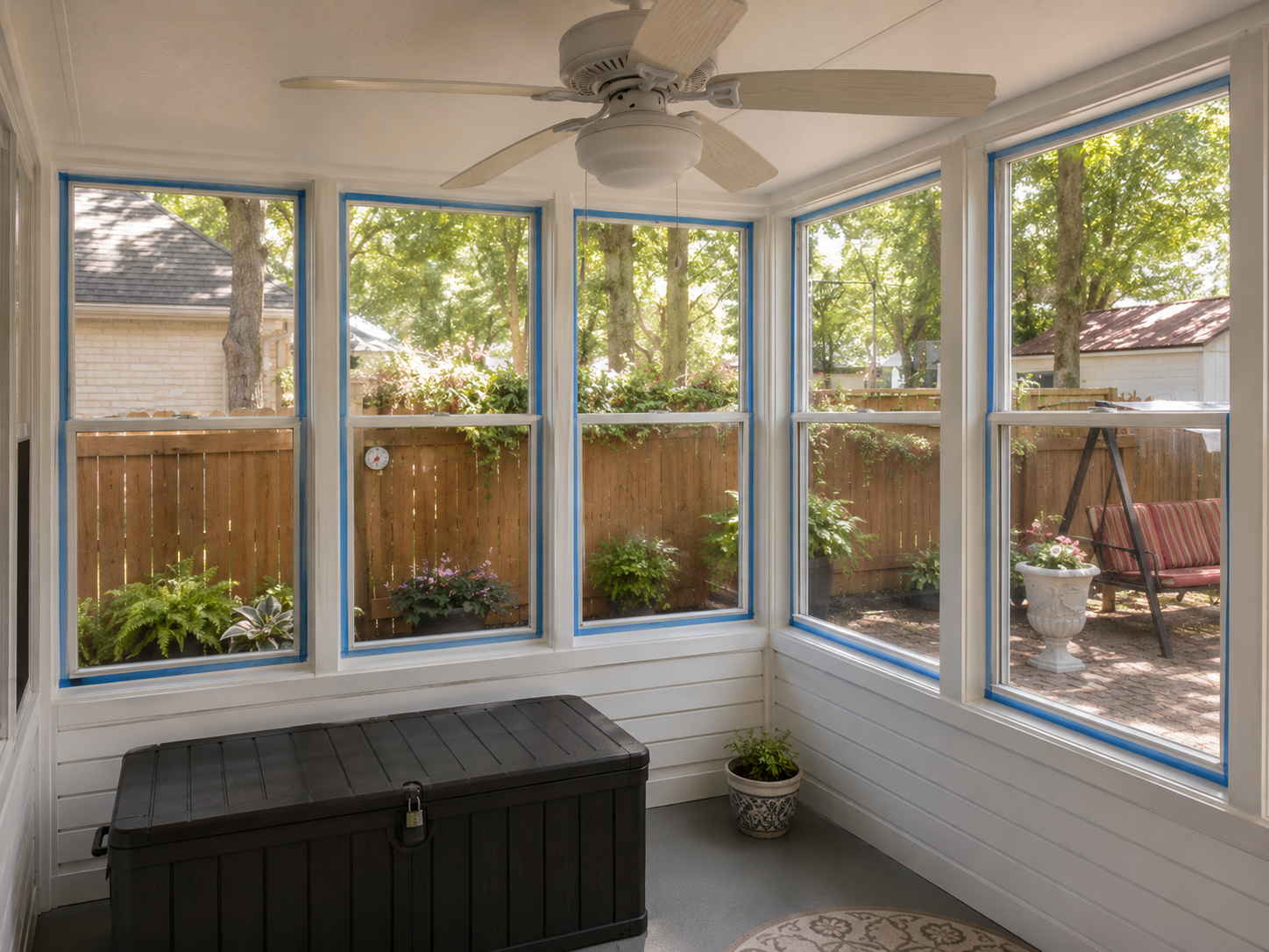 Bright screened porch interior with windows and a ceiling fan